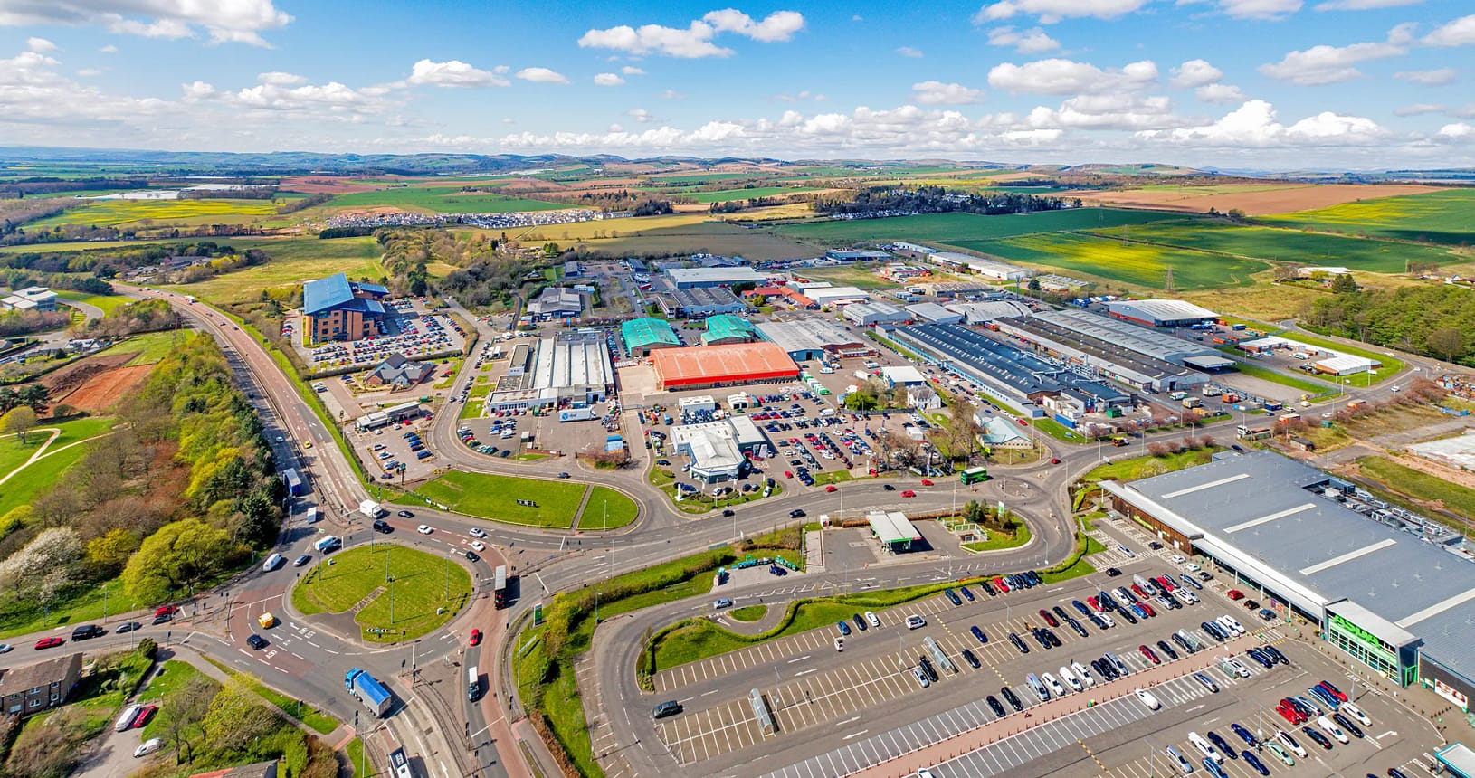 Aerial view of Wester Gourdie Industrial Estate in Dundee showing roundabout, retail units and surrounding commercial area
