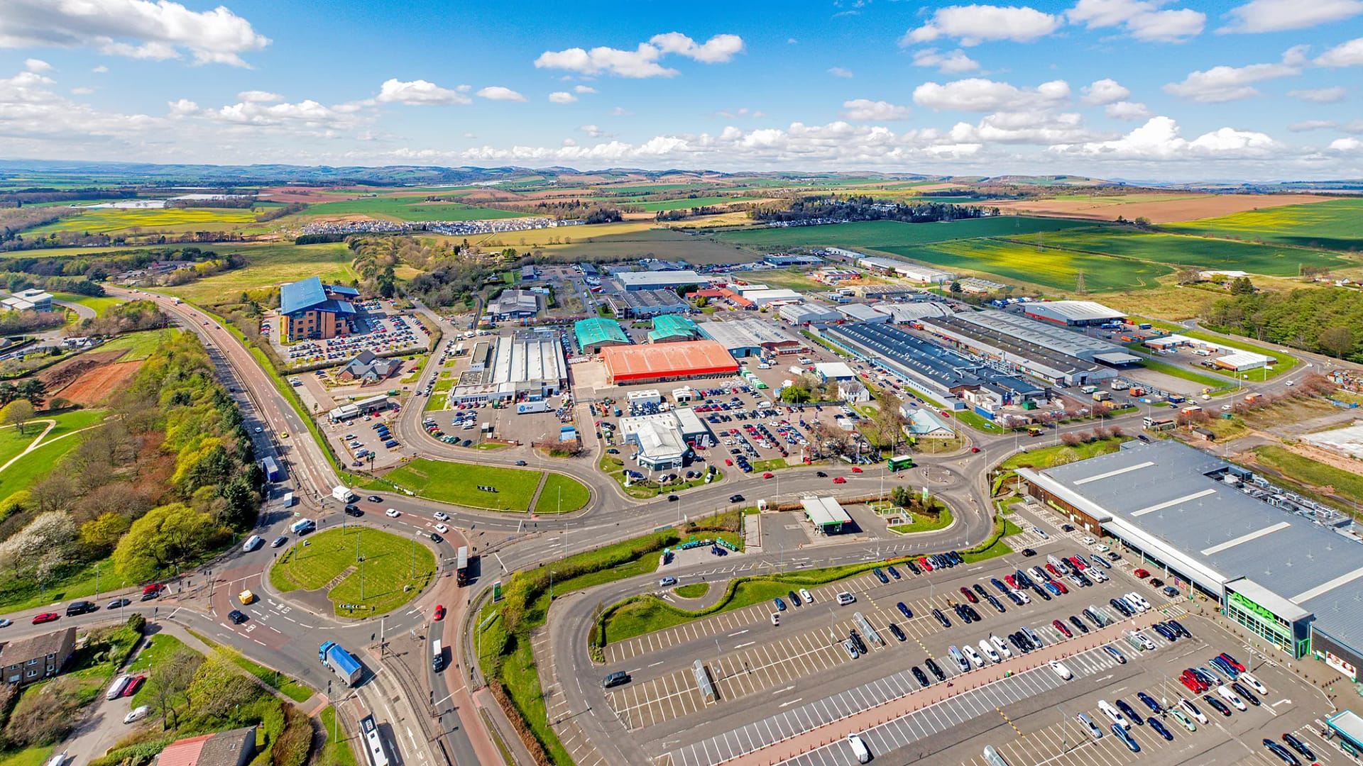 Aerial view of Wester Gourdie Industrial Estate in Dundee showing roundabout, retail units and surrounding commercial area